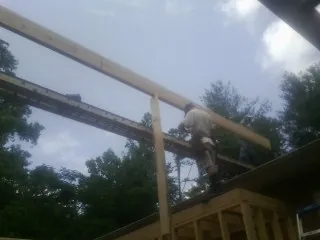 Carpenter setting a ridge beam over a new addition frame — Ice Dam Removal by Roofing Brothers in Harwick