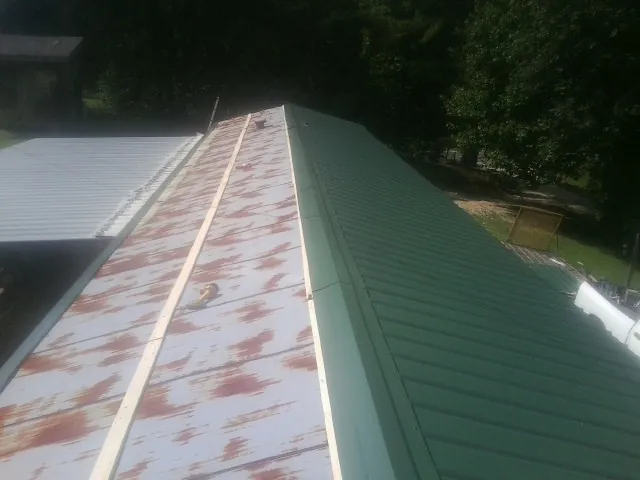 Old rusted panels beside newly installed green metal roofing — Wind Damage Roof Repair by Roofing Brothers in Harwick
