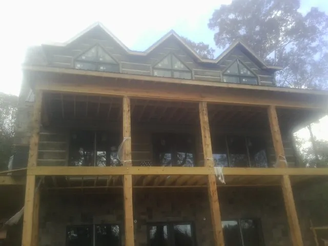 Dormers and porch framing on a large log home under construction — Roof Coating work by our crew in Harwick