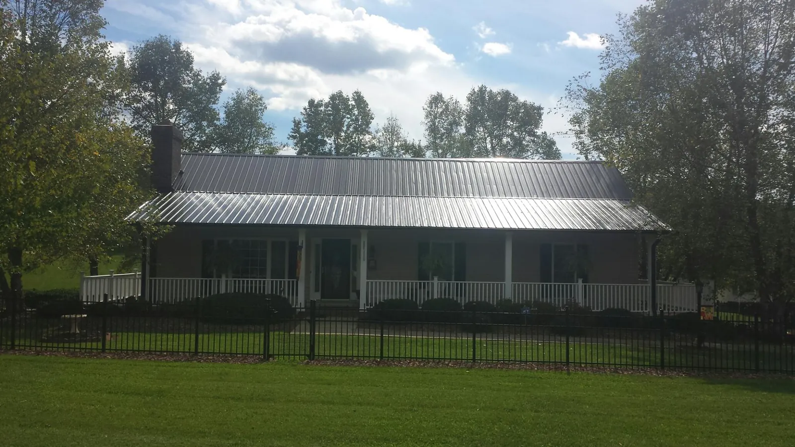 Gray metal roof on a brick ranch with a full width front porch — Gutter Guard Installation work by our crew in Harwick